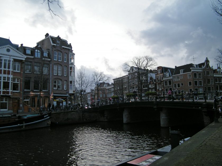 Terrasse au bord d'un canal d'Amsterdam, bateaux amarrés en arrière-plan